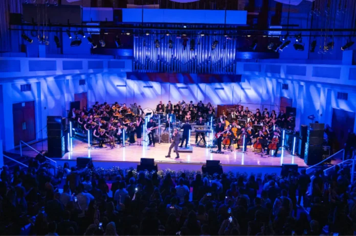 Yandel en el escenario junto a la Orquesta Sinfónica de FIU durante el anuncio de la Beca Yandel Elyte en Miami.